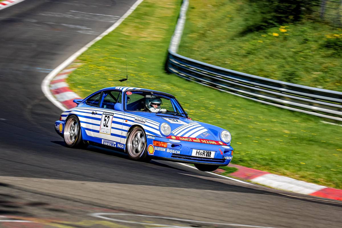 Der blaue Aimpoint-Porsche 964 mit Startnummer 52 in einer Kurve der Nordschleife bei Sonnenschein