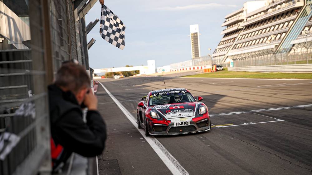 Der Aimpoint-Cayman GT4 überquert die Ziellinie unter der schwarz-weiß karierten Flagge
